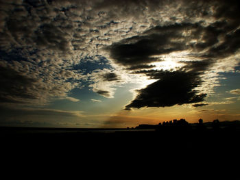 Silhouette of trees against cloudy sky