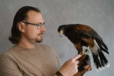Man with eagle buzzard at home. unusual pets and human animal friendship relationships. wild bird on