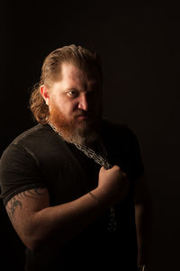 Man looking away while standing against black background