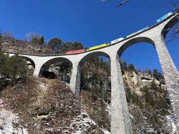 Low angle view of train on railway bridge against blue sky