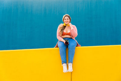 Portrait of woman sitting against wall