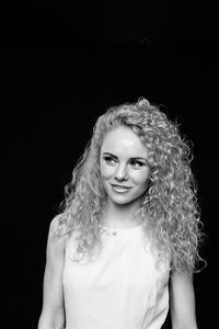 Woman with curly hair standing against black background