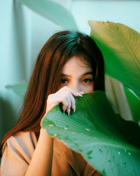 Portrait of young woman by wet plant