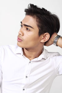 Portrait of young man looking away against white background