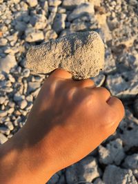 Low section of woman holding pebbles on sand at beach