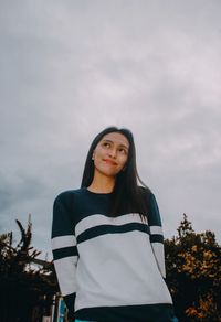 Portrait of young woman standing against sky