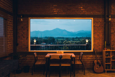 Empty chairs and tables against window at cafe