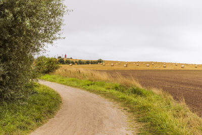 Road amidst field against sky