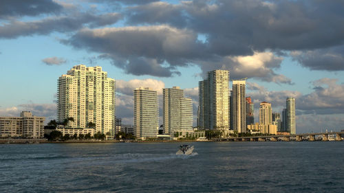 Sea by buildings against sky in city