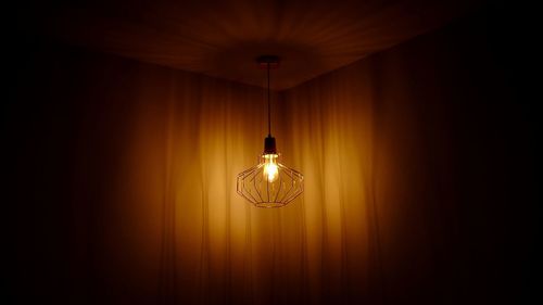 Illuminated pendant light against curtain