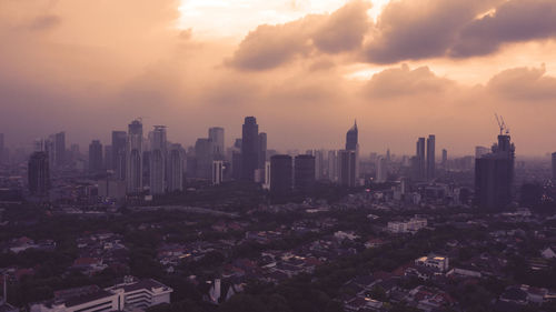 Modern buildings in city against sky during sunset