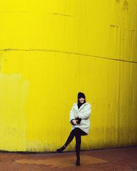 Portrait of young man sitting on yellow wall