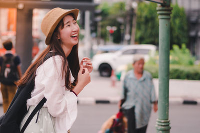 Young woman wearing hat standing on street in city