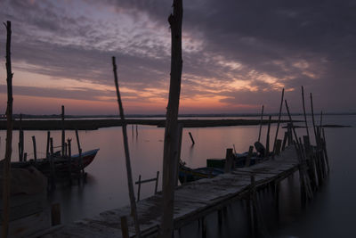 Sailboats moored in sea against sky during sunset