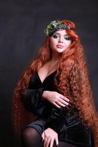 Portrait of sensuous young woman wearing wreath against black background
