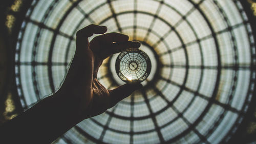 Close-up of hand holding crystal glass against ceiling