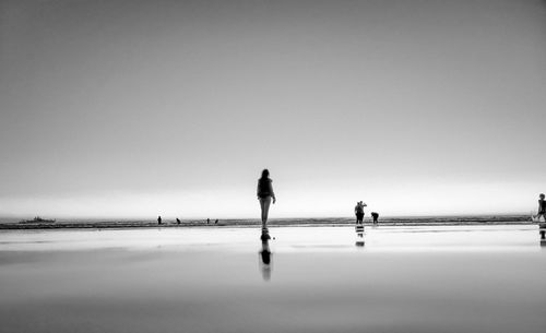 People on beach against clear sky