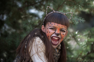 Portrait of girl wearing cheetah costume and face paint in forest