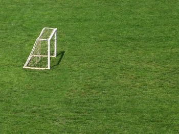 Football field outdoors with small goal with net on terrain covered with green grass
