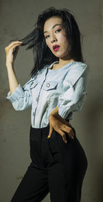 Beautiful young woman standing against wall