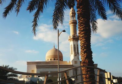 Low angle view of mosque and palm tree against sky