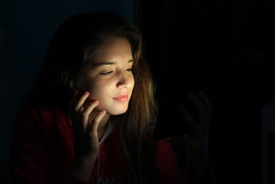 Teenage girl using mobile phone in darkroom at home