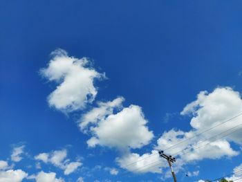 Low angle view of telephone pole against blue sky