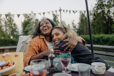 Smiling woman embracing female friend during birthday celebration in back yard