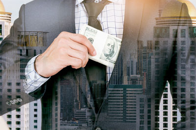 Double exposure of businessman with paper currency against cityscape