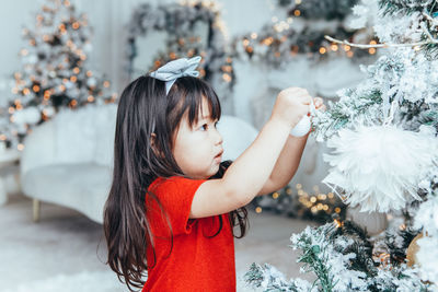 Portrait of young woman standing by christmas tree