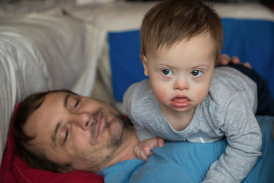 Portrait of father with baby on bed at home