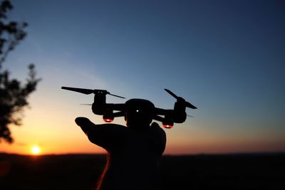 Silhouette man with arms raised against sky during sunset