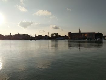 Scenic view of river by buildings against sky