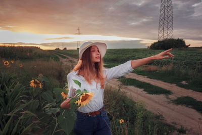 Young beautiful girl in a field of sunflowers. girl in a white shirt and hat. sunset