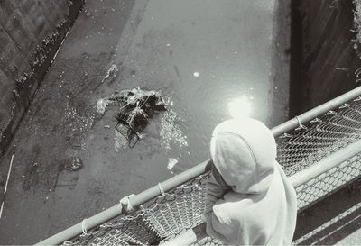 High angle view of girl looking at canal from footbridge