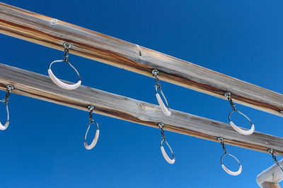 Low angle view of clothes hanging on clothesline against clear blue sky