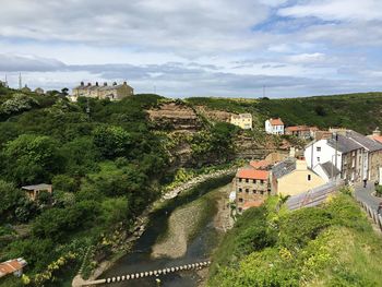 High angle view of houses by sea against cloudy sky