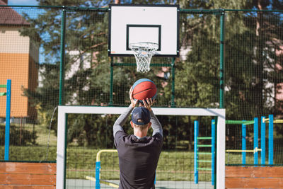 Blond boy in sportswear practices shooting a basketball from behind the three-point line. basketball