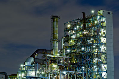 Illuminated factory against sky at night