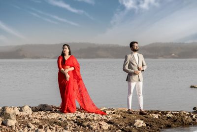 Young couple standing on shore against sky