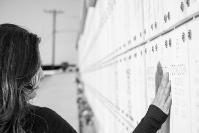 Woman touching wall at cemetery against sky