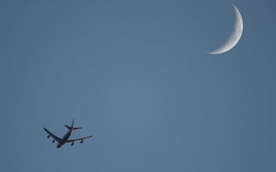 Low angle view of airplane flying against clear blue sky