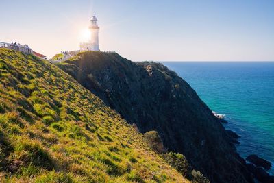 Lighthouse amidst sea and buildings against clear sky