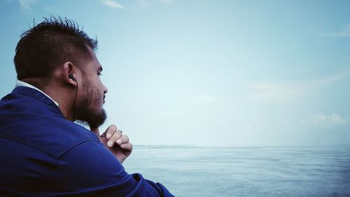 Side view of thoughtful man looking at sea against sky