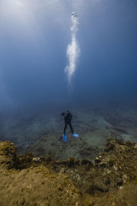 Woman scuba diving over ocean floor in blue sea