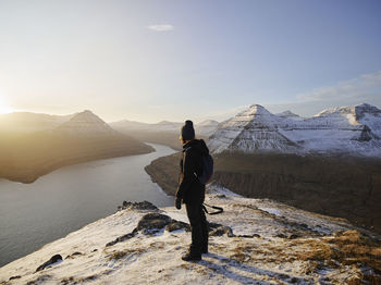 Rear view of man standing on mountain against sky