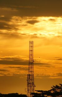 Silhouette crane against dramatic sky during sunset