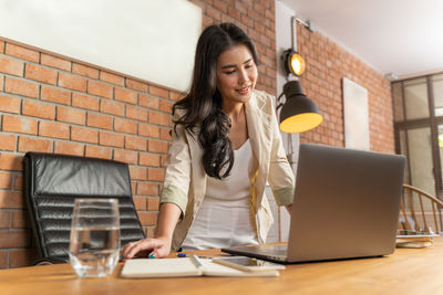 Full length of woman using phone on table