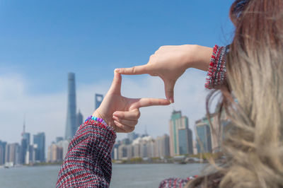 Portrait of woman hand against buildings in city