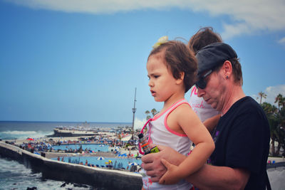 Friends on sea shore against sky